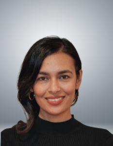 Maira stands and smiles at the camera