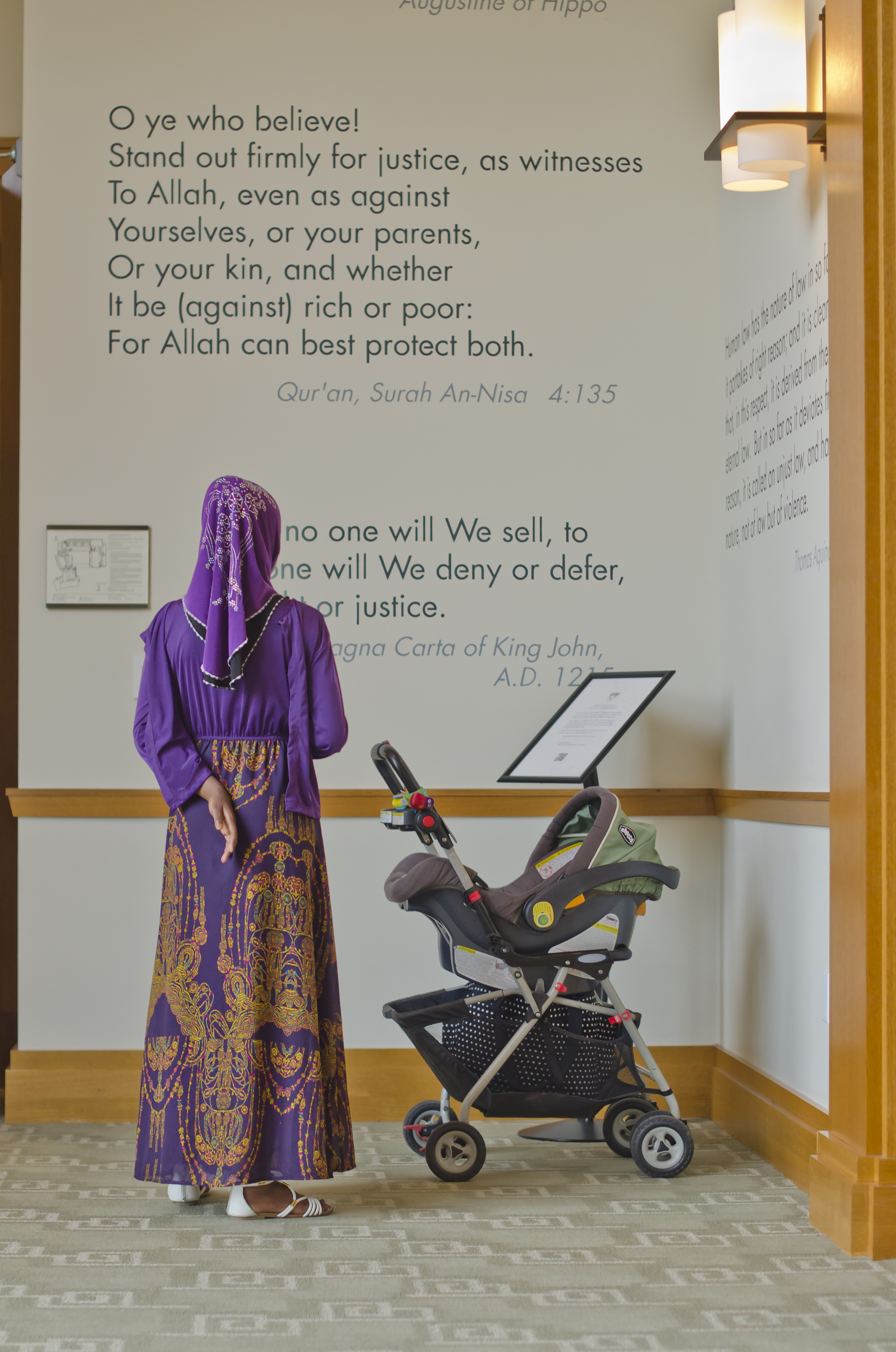 Women with baby carriage reading quotes from a wall display